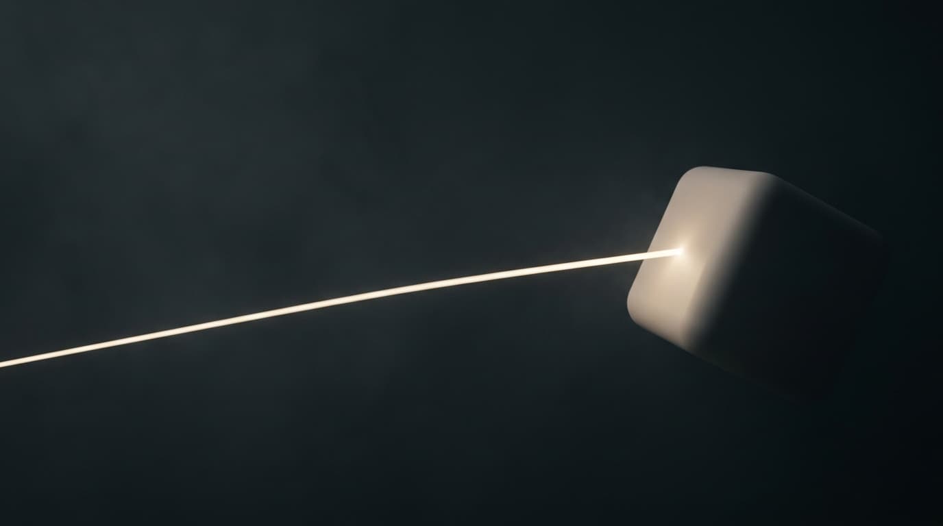 A thin beam of warm light crossing a dark space onto one smooth geometric form.